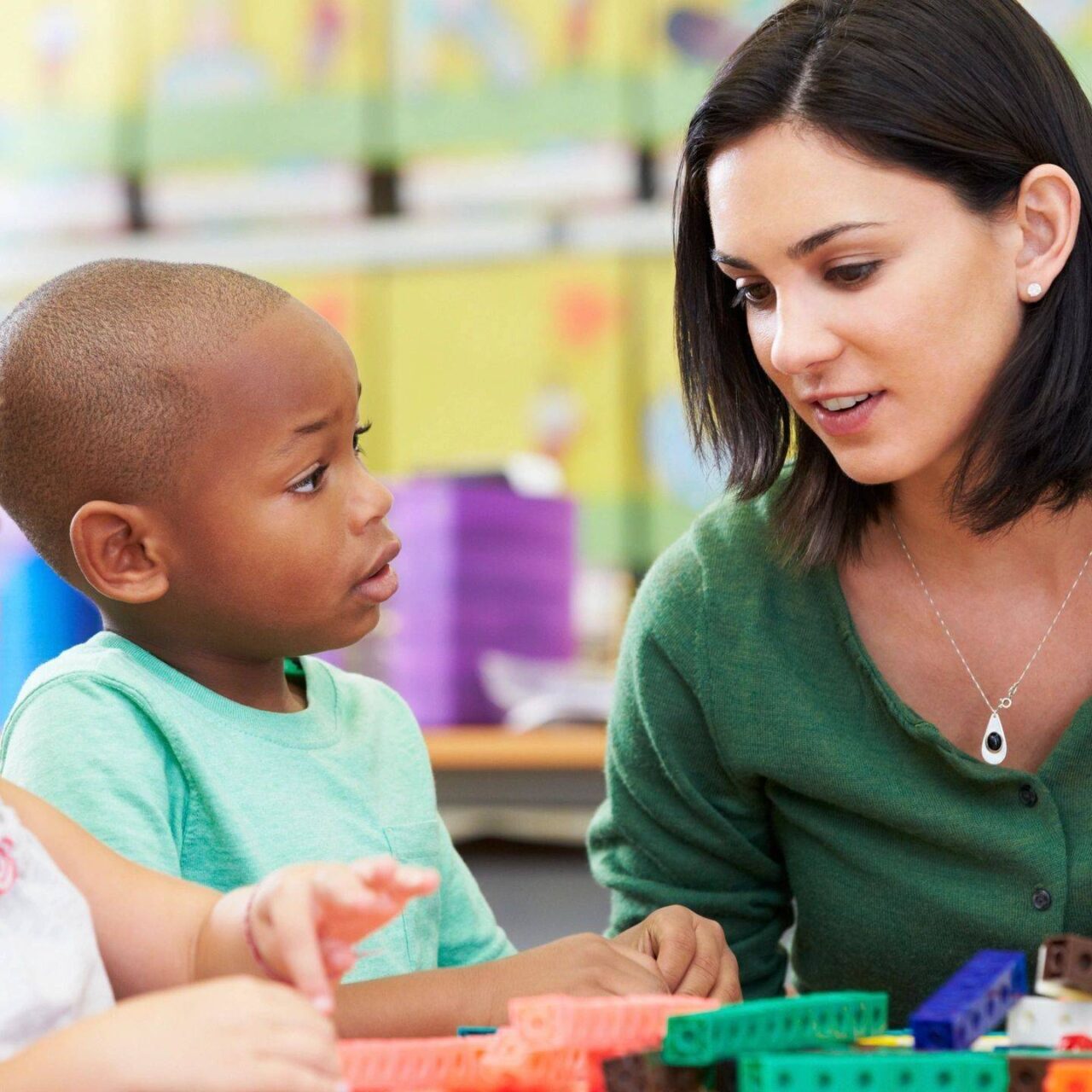 A teacher interacting with a young child in a classroom.